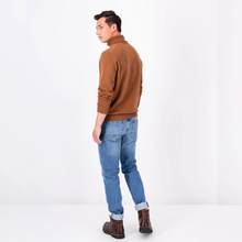 Load image into Gallery viewer, Model looking over shoulder wearing a Walnut Brown polo neck with blue jeans and brown boots

