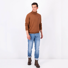 Load image into Gallery viewer, Model wearing the Walnut Brown coloured Fynch Hatton Polo Neck with sleeves pushed up too elbows, wearing blue jeans and brown boots
