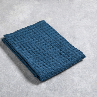Folded blue textured blanket on a gray surface
