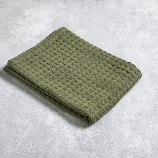Folded green textured blanket on a gray surface