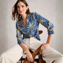 Load image into Gallery viewer, Woman wearing a blue floral blouse sitting on a chair against a neutral background
