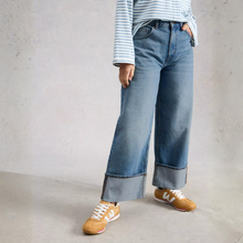 Load image into Gallery viewer, Person wearing blue jeans and brown shoes against a plain background
