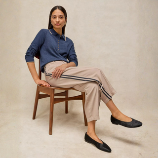 Lady sitting on chair with natural trousers with stripe and blue top