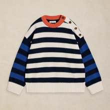 Load image into Gallery viewer, A striped knit sweater laid flat on a light beige background. The sweater has horizontal navy and off-white stripes across the body, royal blue stripes on the sleeves, a coral-orange ribbed crew neck, and three brown buttons on the upper sleeve.
