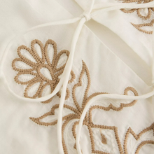 Load image into Gallery viewer, Close-up of beige embroidered fabric with floral patterns on a beige background
