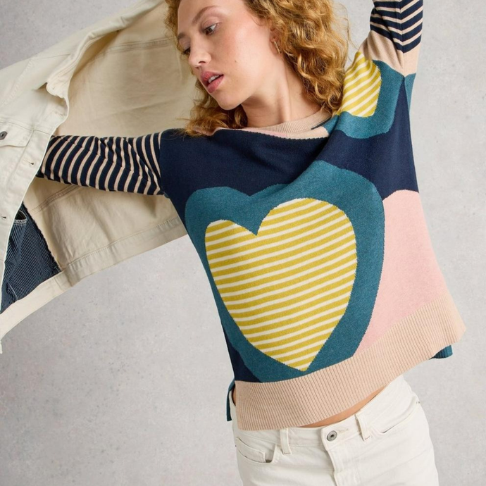 Woman wearing a colorful sweater with a heart design on a plain background