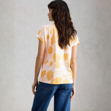 Load image into Gallery viewer, Woman wearing a yellow floral blouse and blue jeans against a gray background
