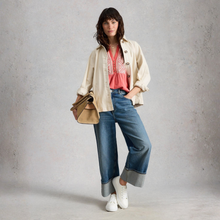Load image into Gallery viewer, Woman wearing a beige jacket, pink top, blue jeans, and white sneakers against a gray background
