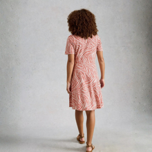 Load image into Gallery viewer, Woman wearing a red patterned dress against a gray background
