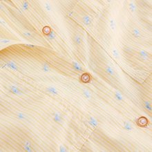 Load image into Gallery viewer, Close-up of a yellow shirt with small blue patterns and pink buttons.

