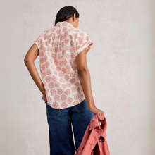Load image into Gallery viewer, Woman wearing a floral blouse and jeans, holding a pink jacket against a plain background
