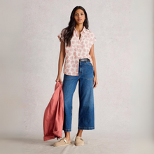 Load image into Gallery viewer, Woman wearing a floral blouse and blue jeans holding a pink jacket against a plain background
