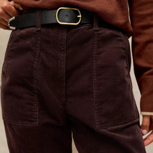 Load image into Gallery viewer, Close-up of a person wearing dark brown corduroy pants with a black leather belt featuring a gold buckle.
