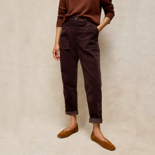 Load image into Gallery viewer, A person wearing dark brown corduroy trousers, a brown long-sleeve top, and brown suede flats, standing against a textured beige studio backdrop.
