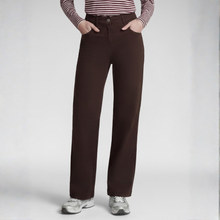 Load image into Gallery viewer, A person wearing dark brown wide-leg pants, a red and white striped long-sleeve top, and gray sneakers, standing against a light gray studio background.

