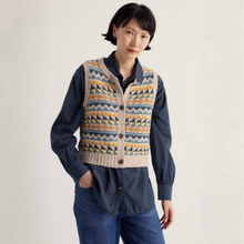 Load image into Gallery viewer, A woman wearing a navy blue corduroy button-up shirt layered under a beige knit vest with a multicolor geometric pattern, paired with blue jeans, against a plain off-white background.
