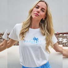 Load image into Gallery viewer, Model wearing white t-shirt with blue writing in the middle saying Paradise
